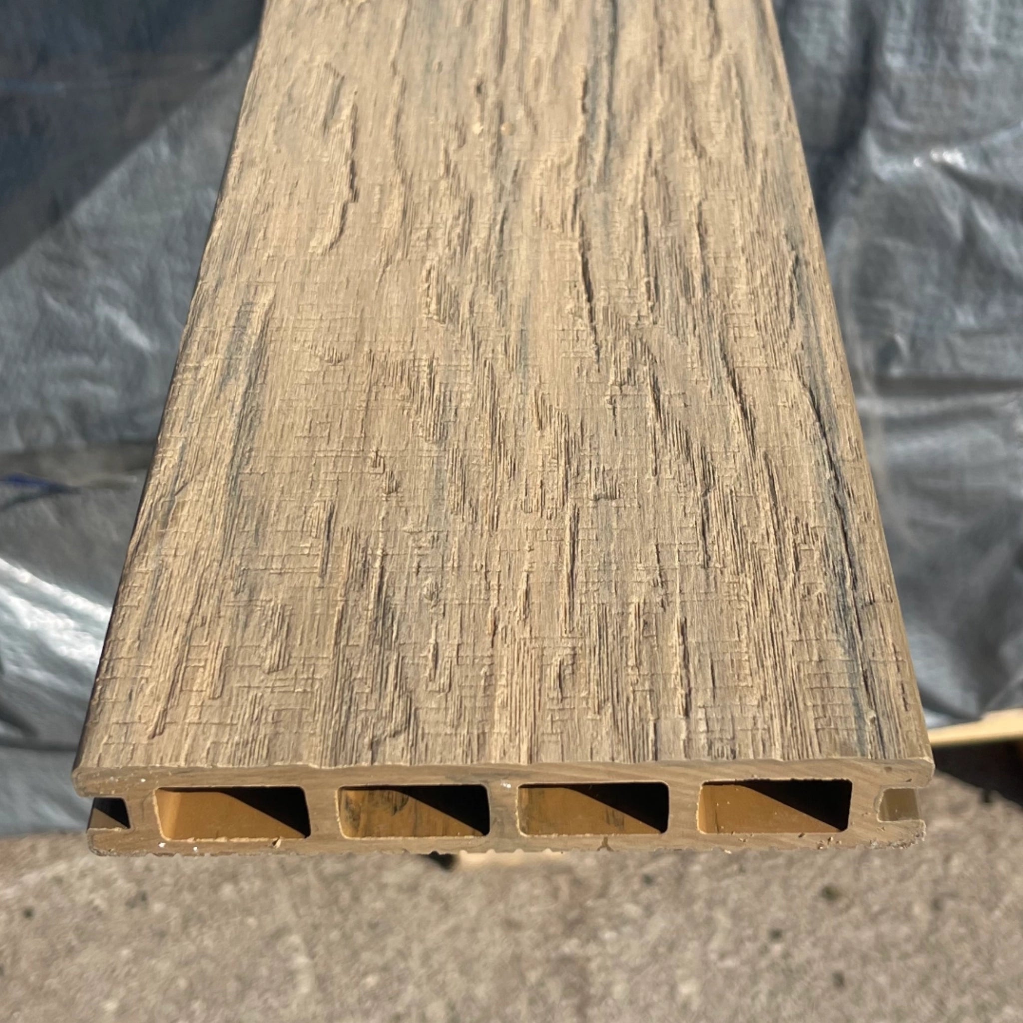 composite dekcing board with a textured surface and horizontal slats on a gray background