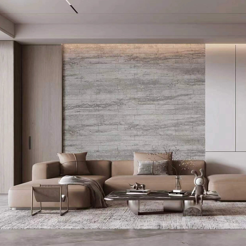 Modern living room with a beige sectional sofa, coffee table, and decorative items against a flexistone grey travertine peel and stick wall
