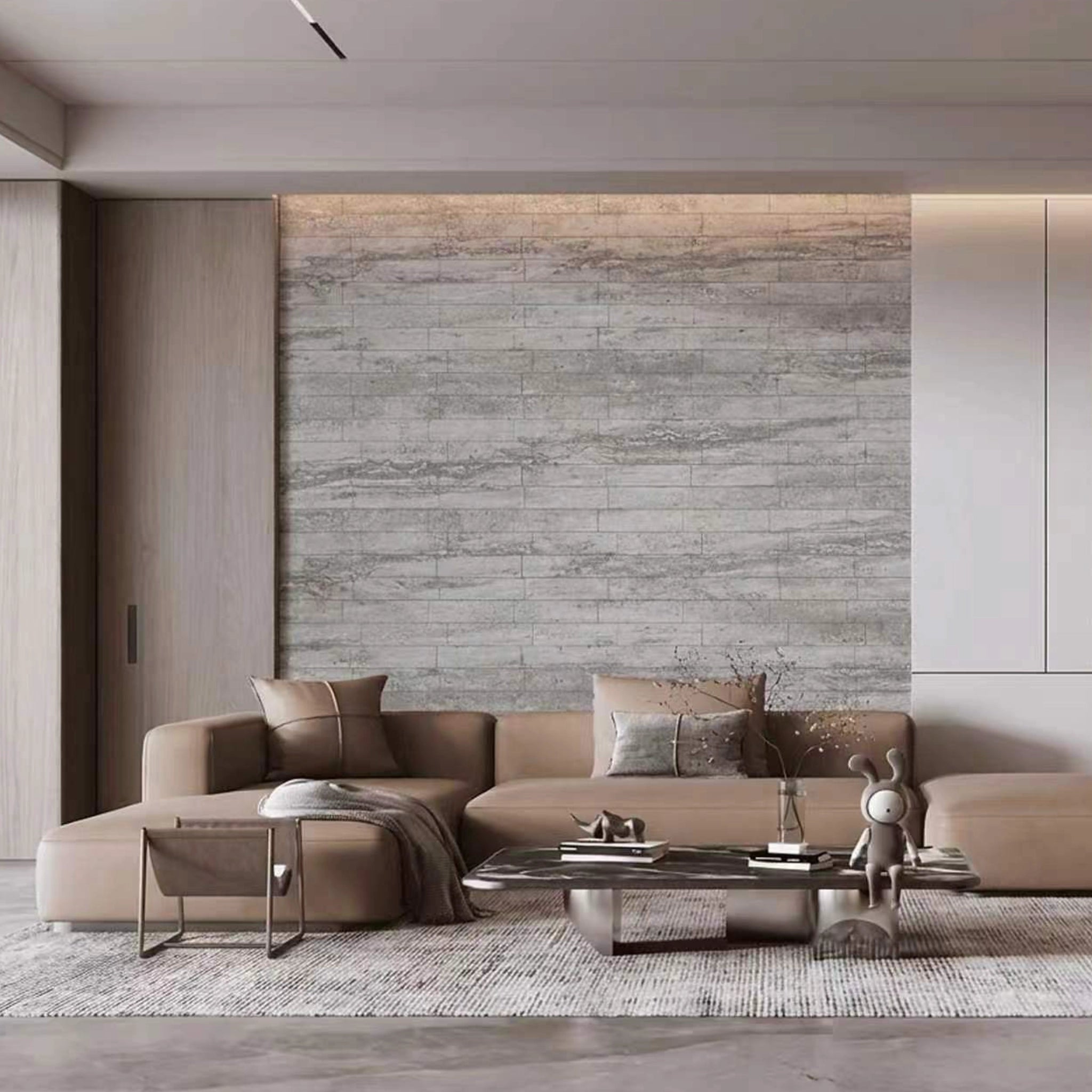 Modern living room with a beige sectional sofa, coffee table, and decorative items against a flexistone grey travertine peel and stick wall