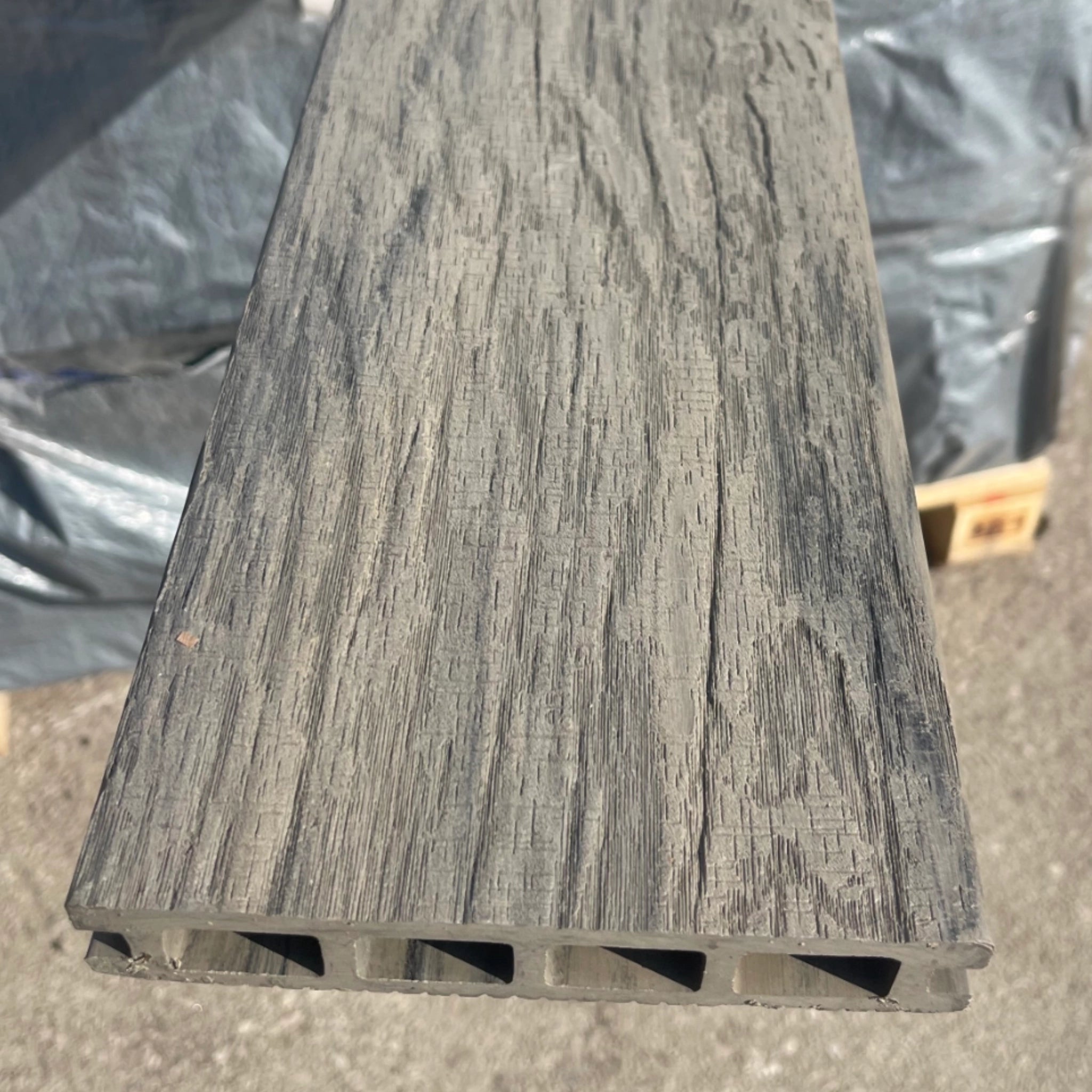 composite deck board with a textured surface on a concrete floor.