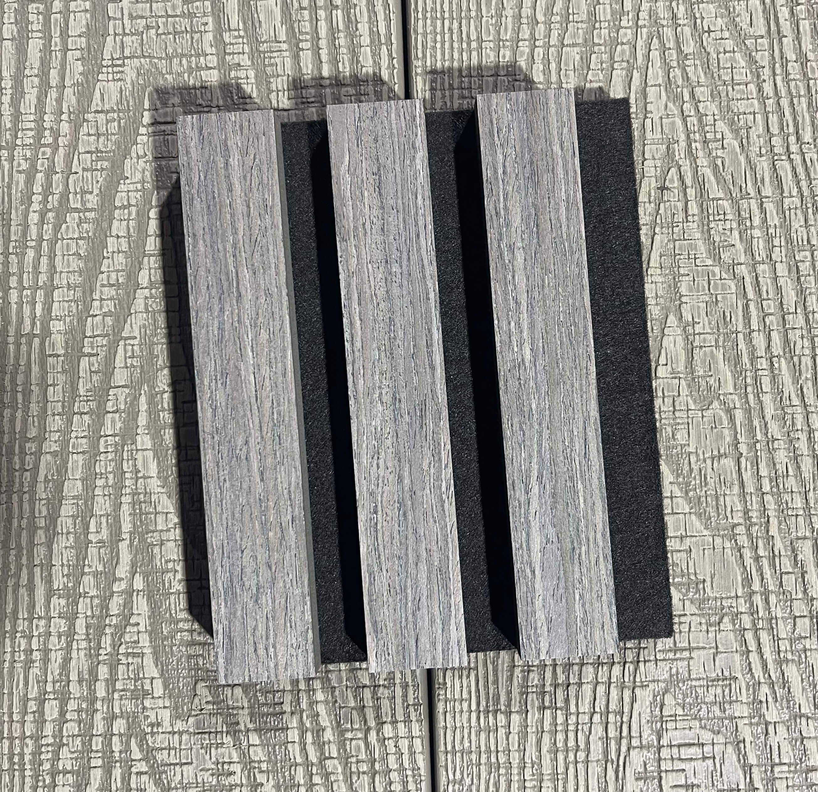 Three rectangular wooden slats on a textured surface