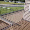 Wooden deck with glass railing overlooking a grassy area with mobile homes.