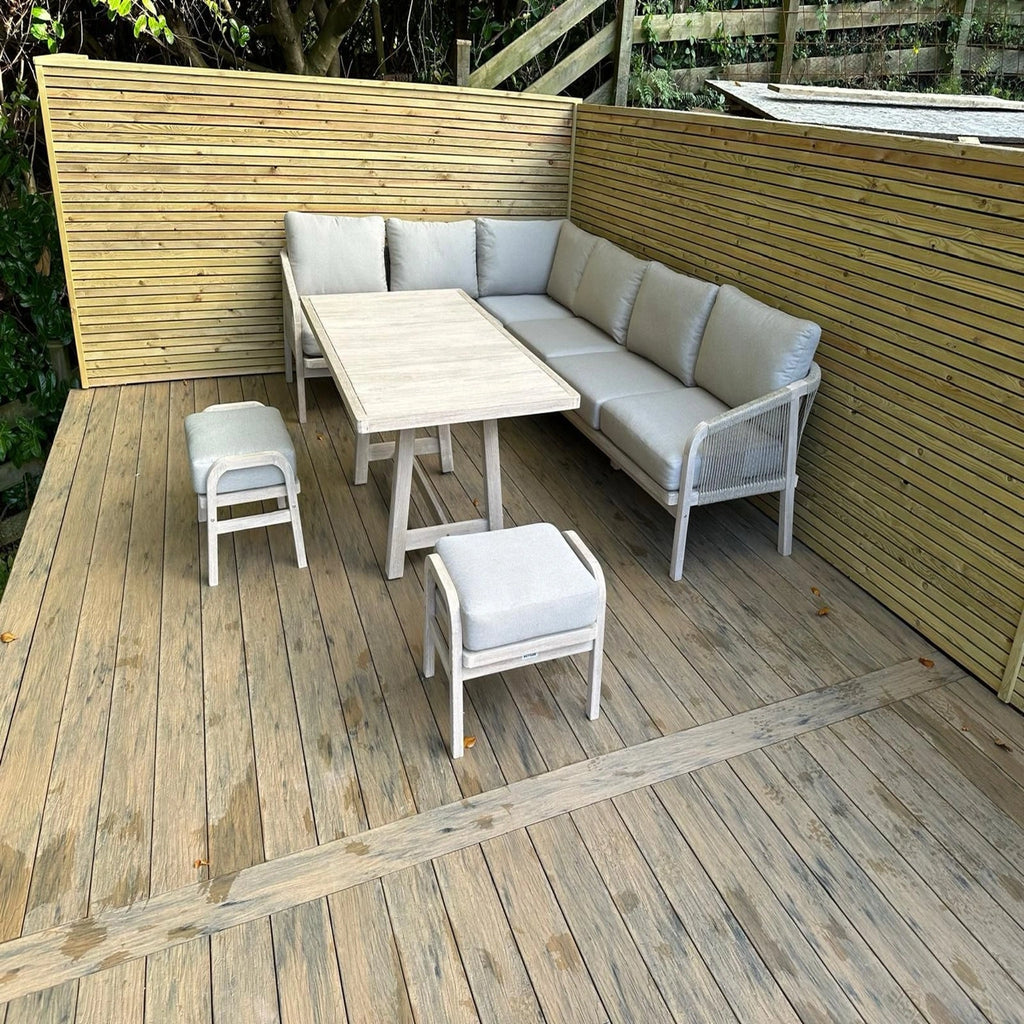 Outdoor furniture set on a beige driftwood composite decking with a wooden wall in the background.