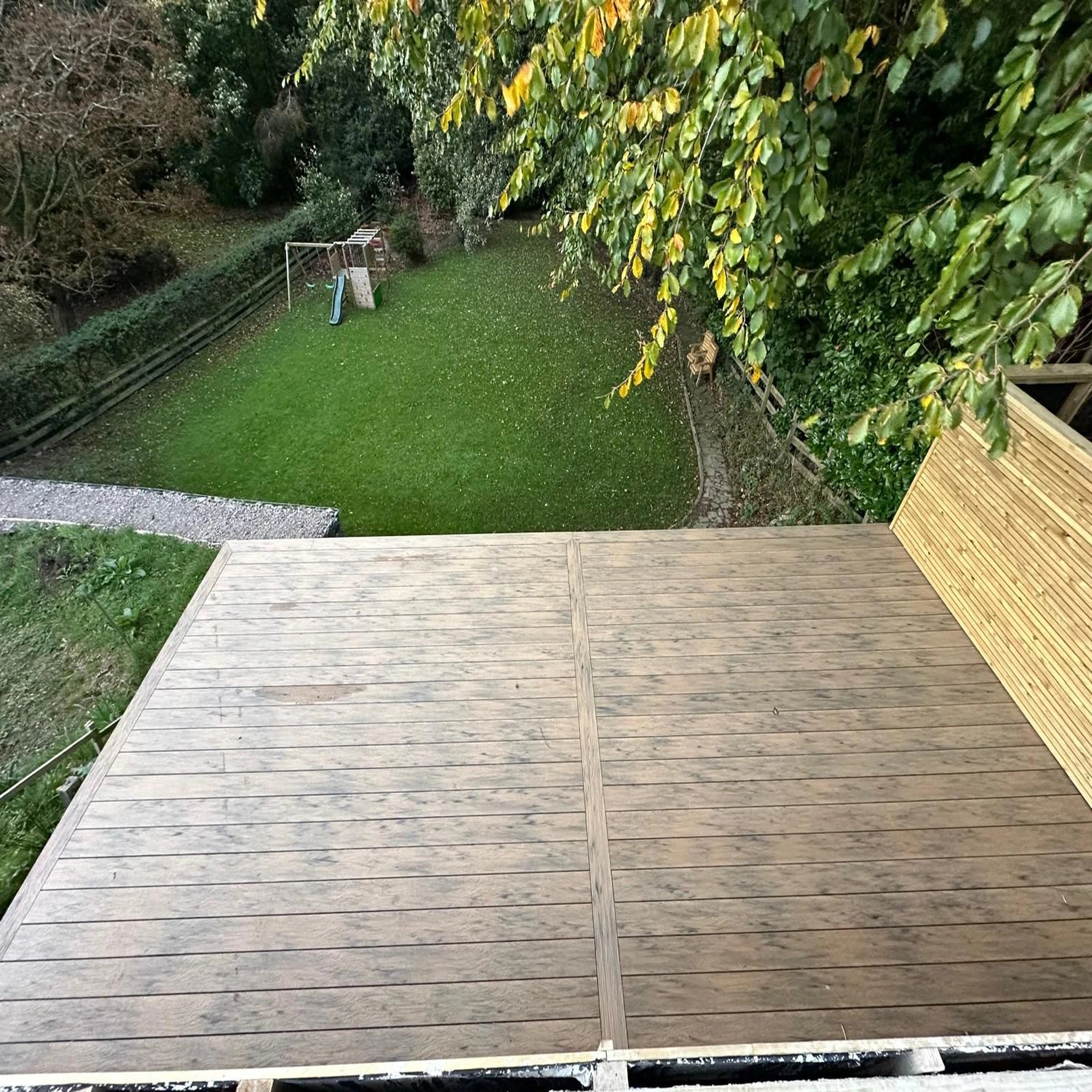 beige driftwood composite deck overlooking a grassy yard with trees