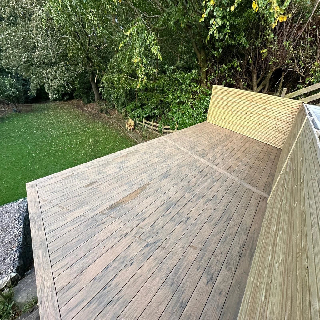 beige composite decking with a view of green grass and trees
