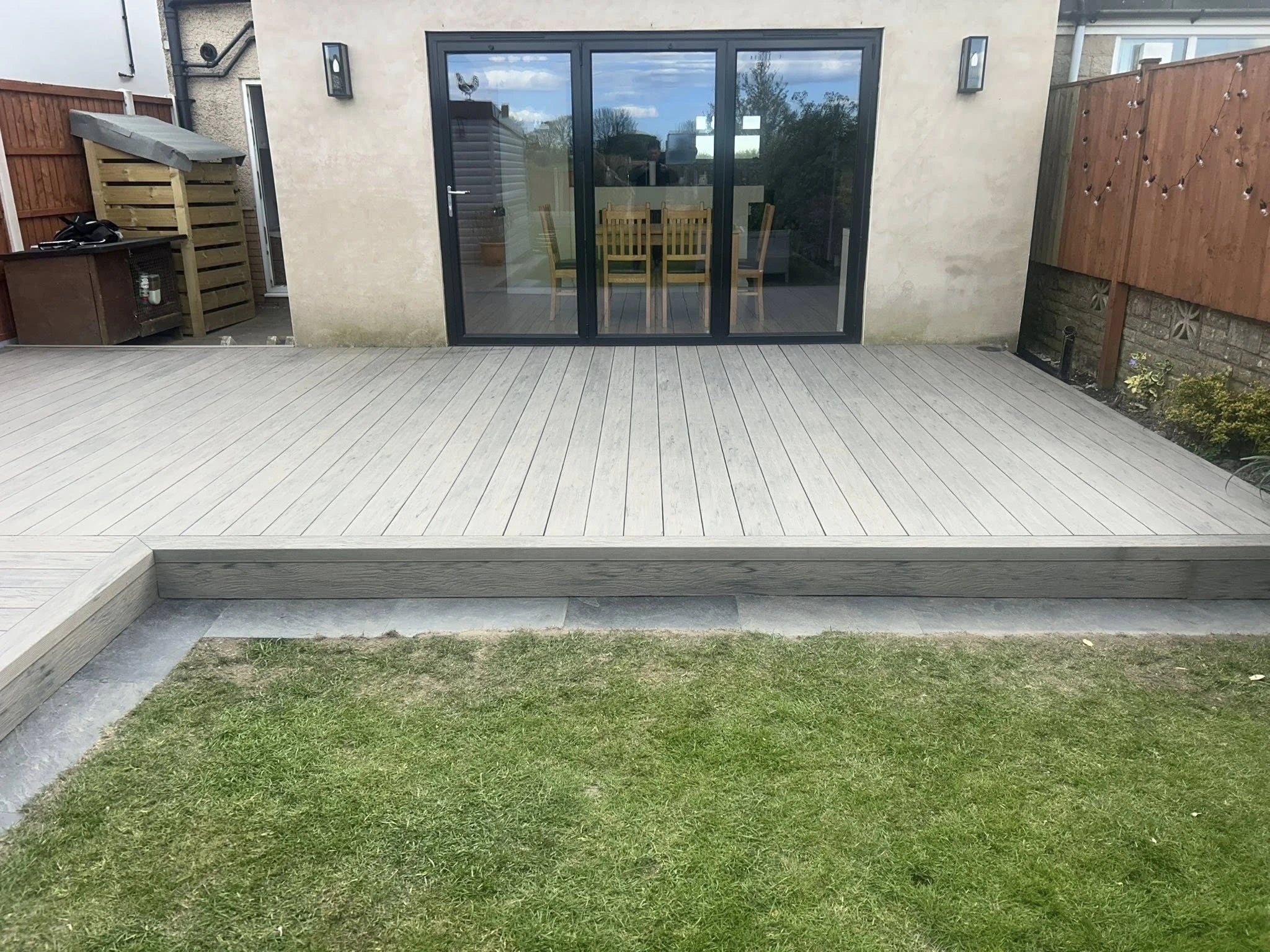 grey driftwood decking in a garden setting with lawn and black doors