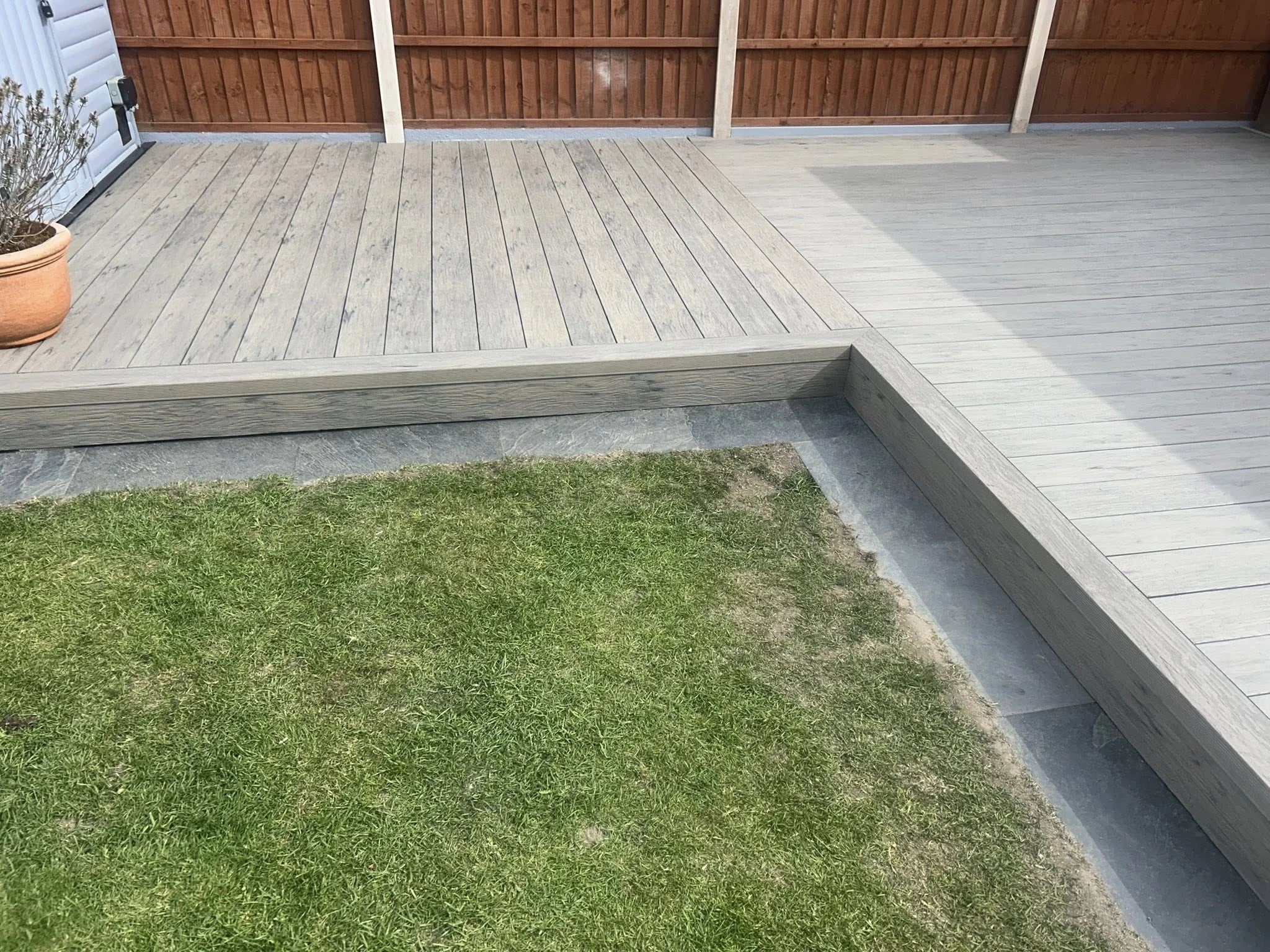 grey driftwood decking in a garden setting with lawn and wood fence