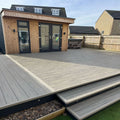 grey driftwood composite deck with a modern house in the background