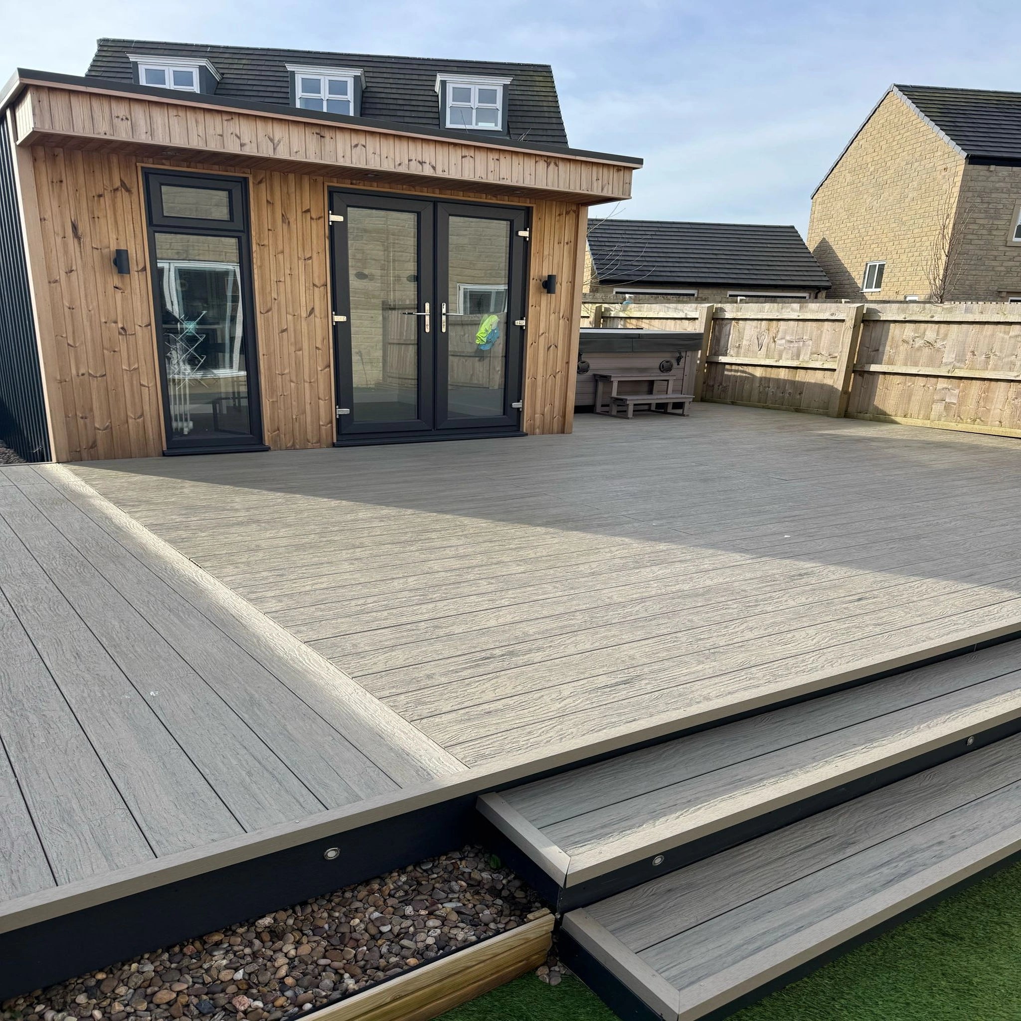 grey driftwood composite deck with a modern house in the background