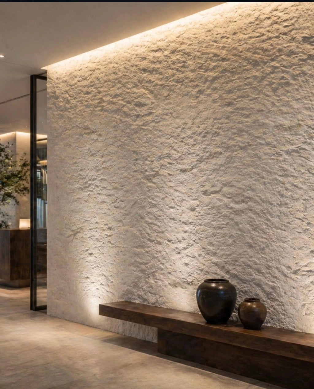 flexistone off white rough granite wall with a wooden shelf and decorative vases in a modern interior setting.